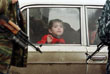 Мальчик смотрит из окна автомобиля на российских солдат на контрольно-пропуском пункте "Кавказ" из Ингушетии в Чечню. 24 декабря 1999 год.