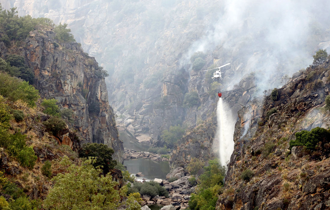 Вертолет сбрасывает воду на лесной пожар вблизи природного парка Аррибес-дель-Дуэров в Саламанке, Испания