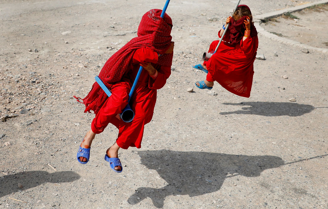 Дети катаются на качелях в первый день мусульманского праздника Курбан-байрам в Кабуле, Афганистан