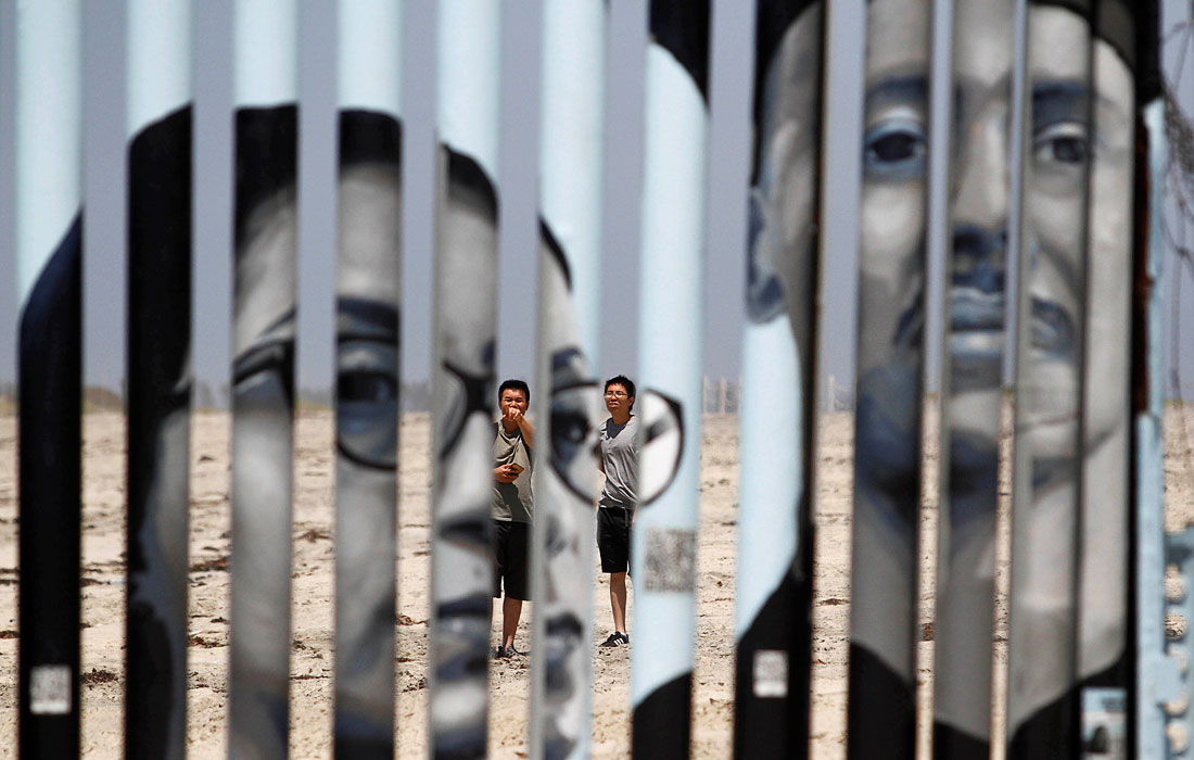 Туристы смотрят на стену разделяющую Мексику и США в Тихуане