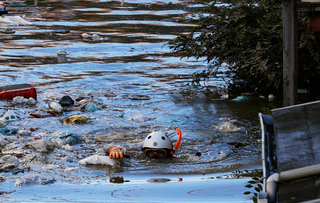 Спасатель вплавь проверяет затопленный жилой район в Кавасаки