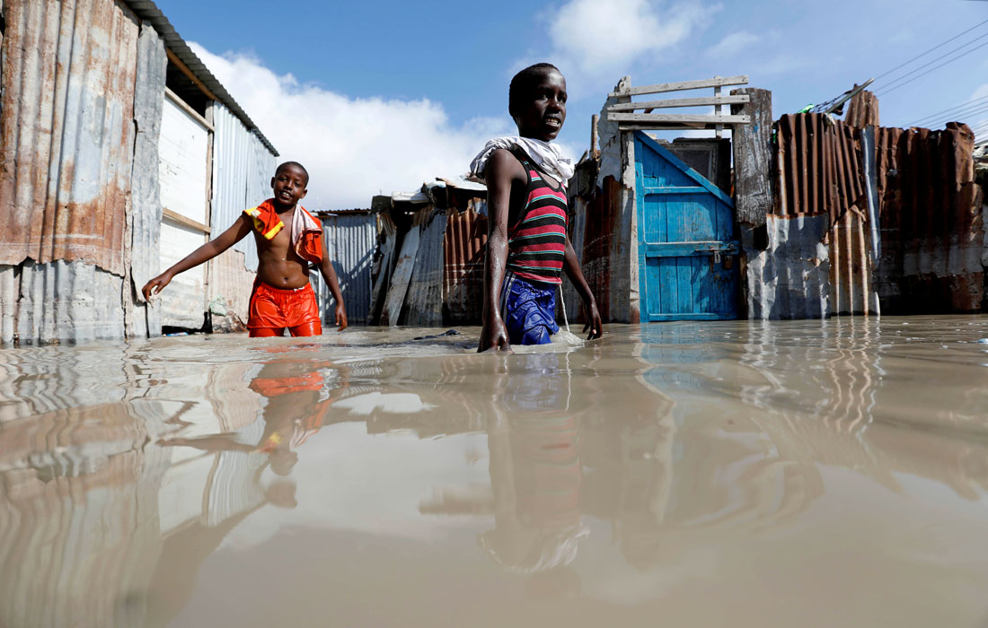Сомалийские дети пробираются через паводковые воды после сильного дождя в Могадишо, Сомали