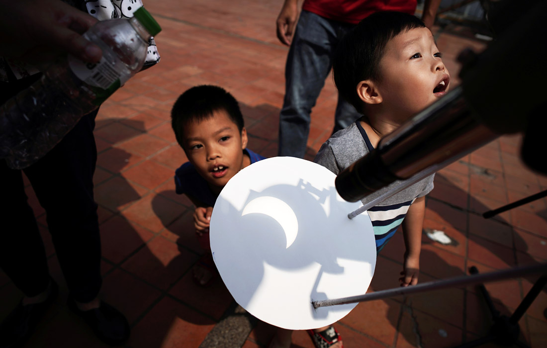 Дети наблюдают частичное солнечное затмение в Бангкоке, Таиланд