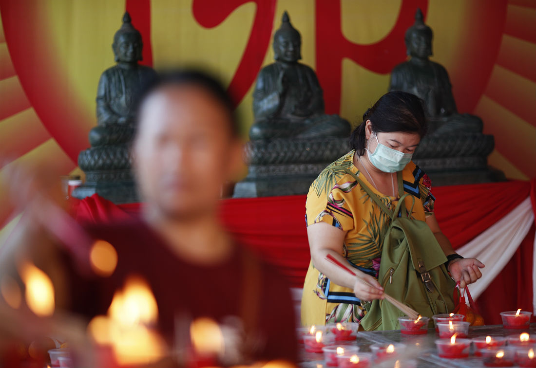 Женщина зажигает благовония в Храме Лотоса и Дракона в Бангкоке. Таиланд