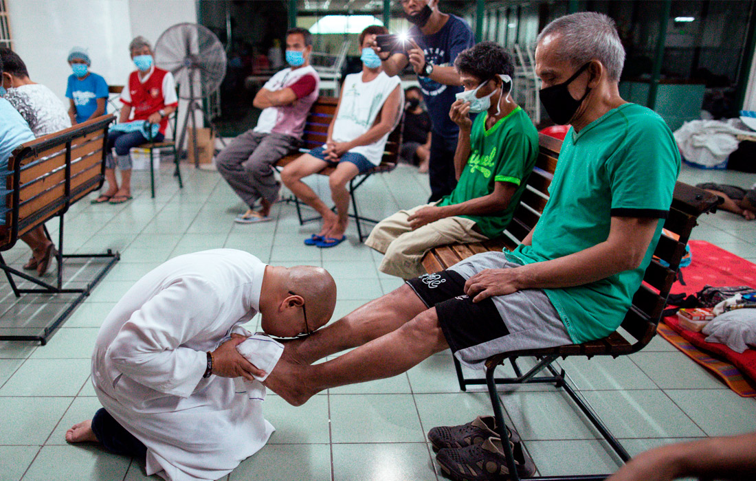 Католический священник проводит омовение ног прихожанам в Великий четверг в Маниле, Филиппины