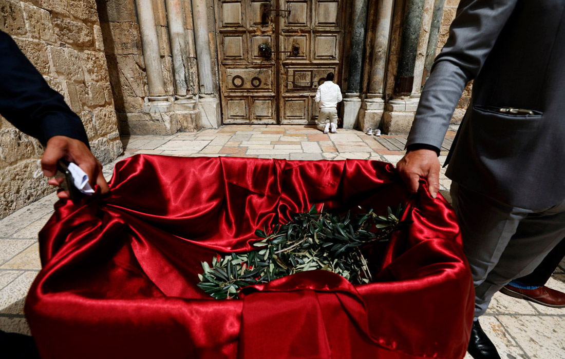 Мужчина молится перед дверьми храма Гроба Господня, закрытого на карантин из-за коронавируса, в Иерусалиме