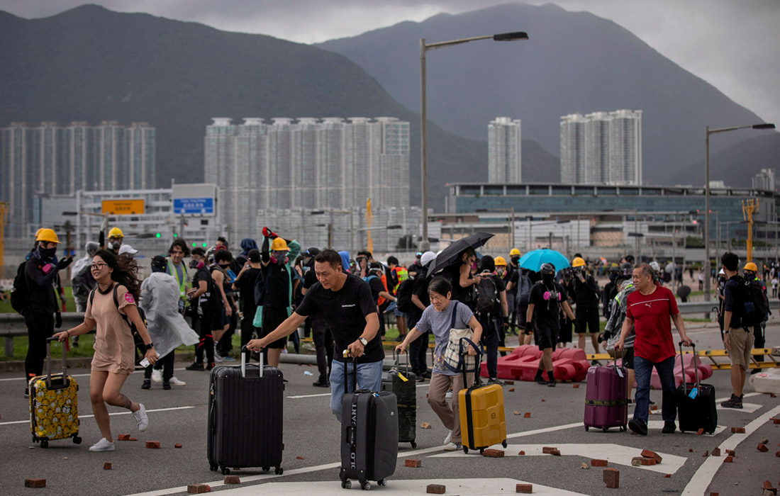 Пассажиры с багажом обходят кирпичи и баррикады после того, как были заблокированы дороги в Международный аэропорт Гонконга. 1 сентября.