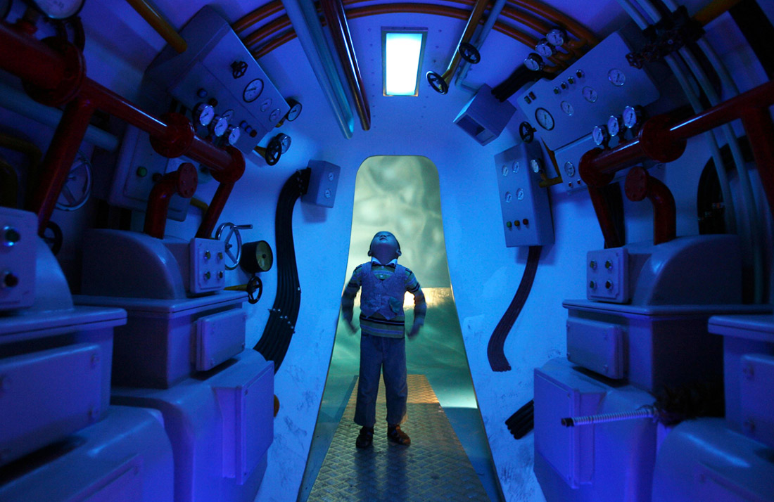 Мальчик изучает модель подводной лодки в Детском музее Шанхая, Китай