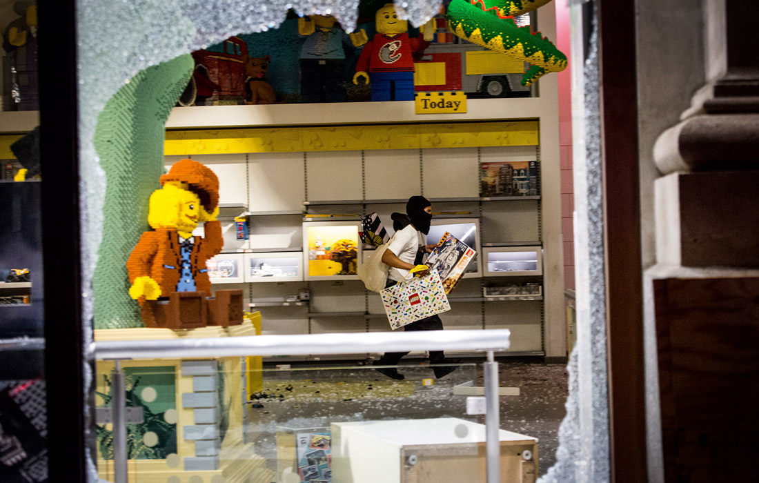Мародер выносит вещи из разграбленного магазина в Нью-Йорке