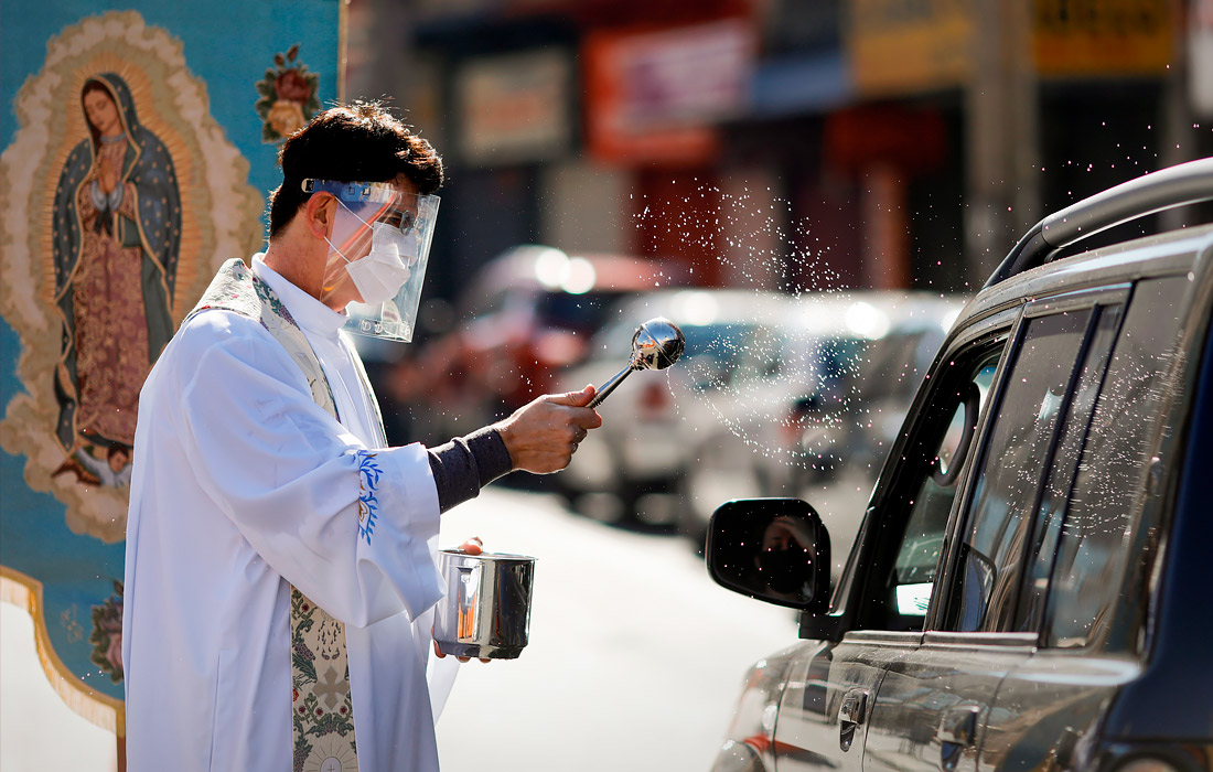 Католический священник окропляет святой водой водителей в Куритибе, Бразилия