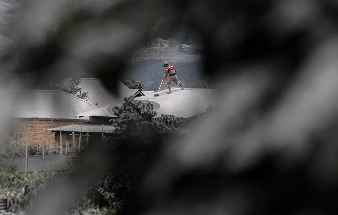 Житель деревни Наман Теран в индонезийской провинции Северная Суматра убирает вулканический пепел с крыши своего дома. 10 августа вулкан Синабунг выбросил столб пепла высотой более пяти километров.
