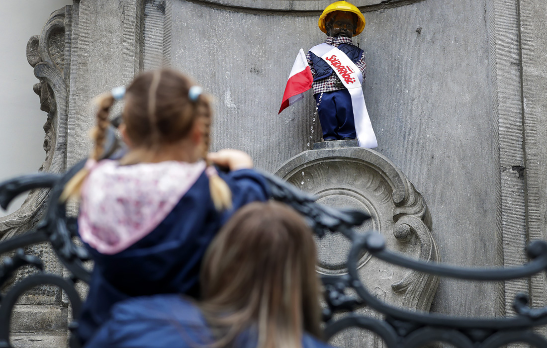Дети смотрят на скульптуру Писающего мальчика, одетого по случаю 40-летия профсоюзного движения Solidarnosc в Брюсселе