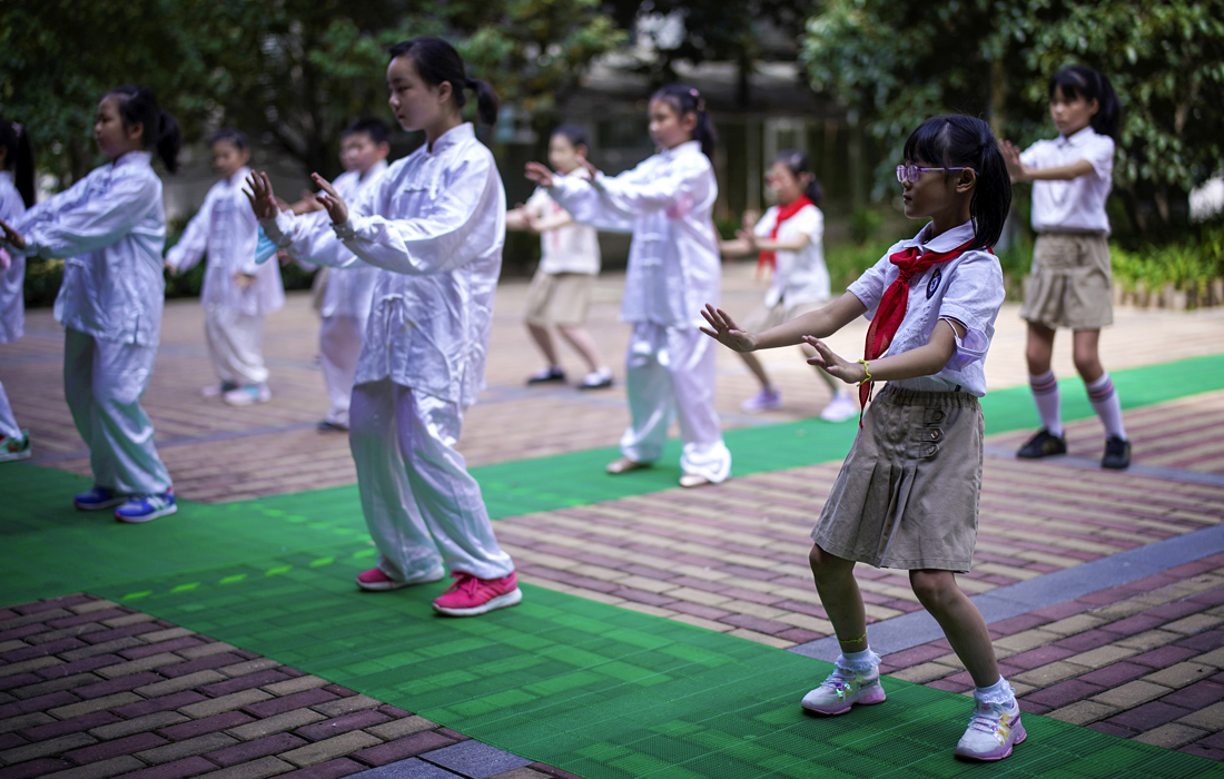 Учащиеся во время занятий тай-чи во дворе одной из начальных школ в китайском городе Ухань