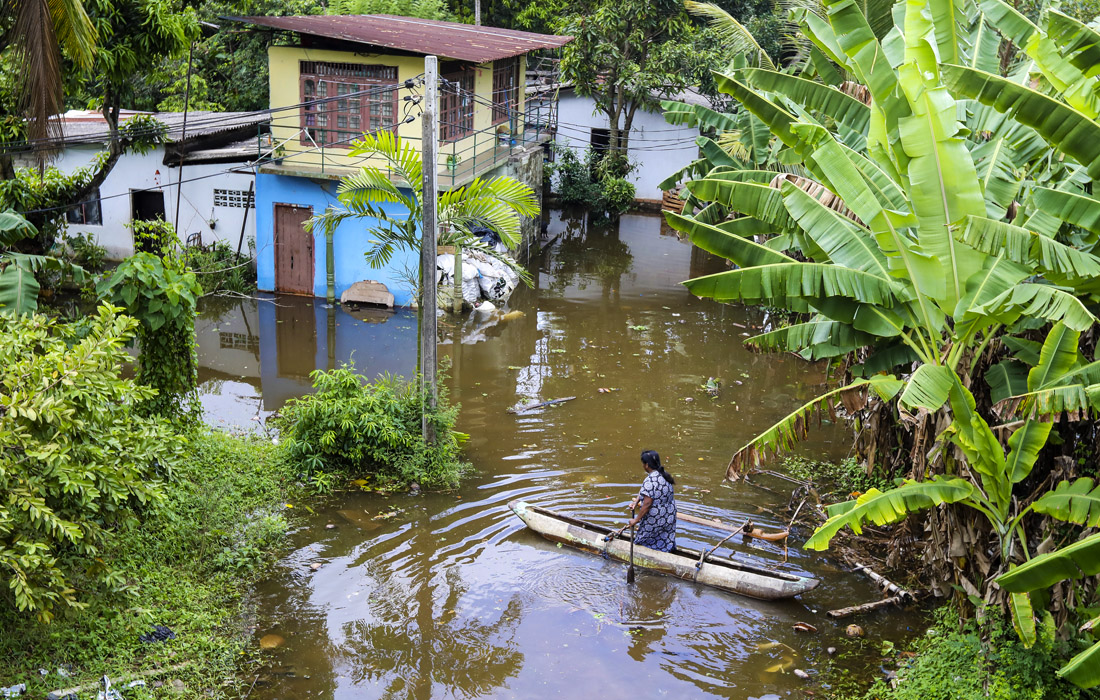 Женщина пробирается по затопленной дороге на небольшой лодке после сильного дождя в Коломбо, Шри-Ланка