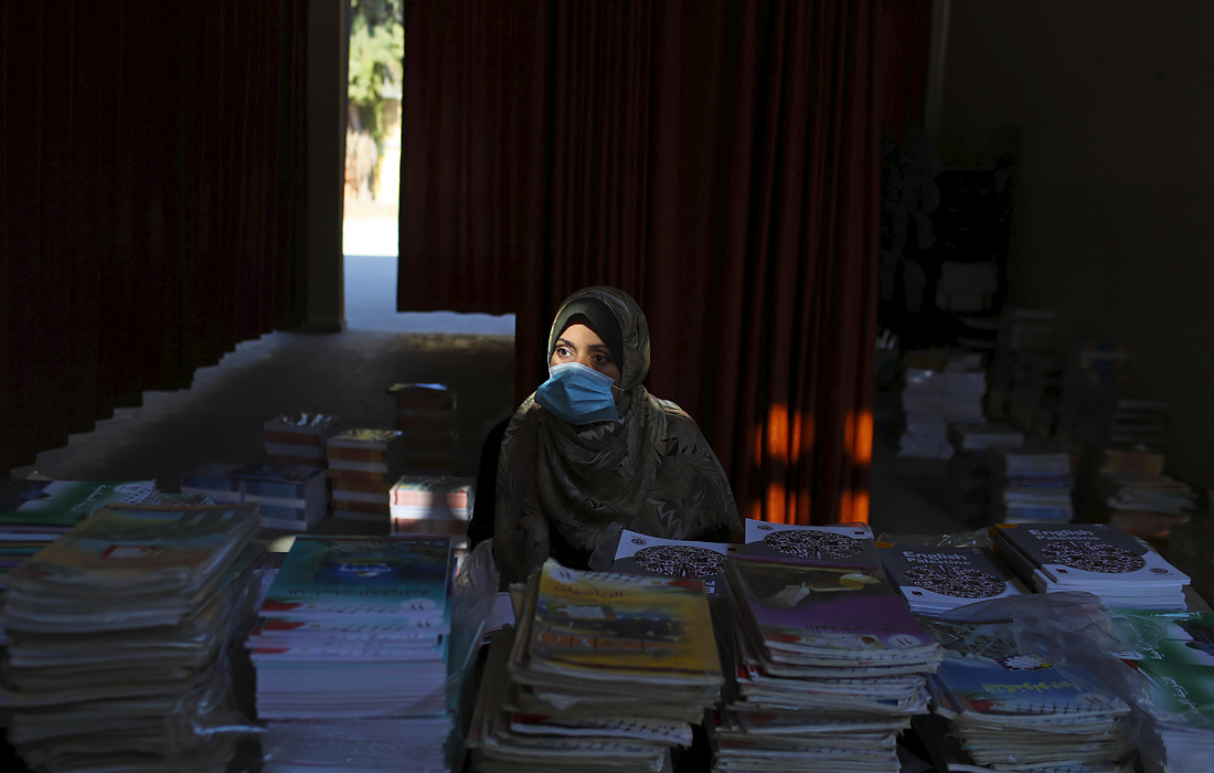 Министерство образования Палестины начало подготовку к открытию школ в условиях вспышки коронавируса. На фото: учительница раздает книги ученикам в школе на севере сектора Газа.

