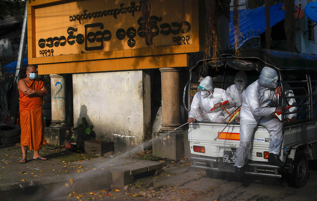 Добровольцы вступают в борьбу с пандемией COVID-19 в Мьянме, поскольку медицинские работники перегружены. На фото: буддийский монах наблюдает, как добровольцы из городской благотворительной группы We Love Lanmadaw дезинфицируют территорию.