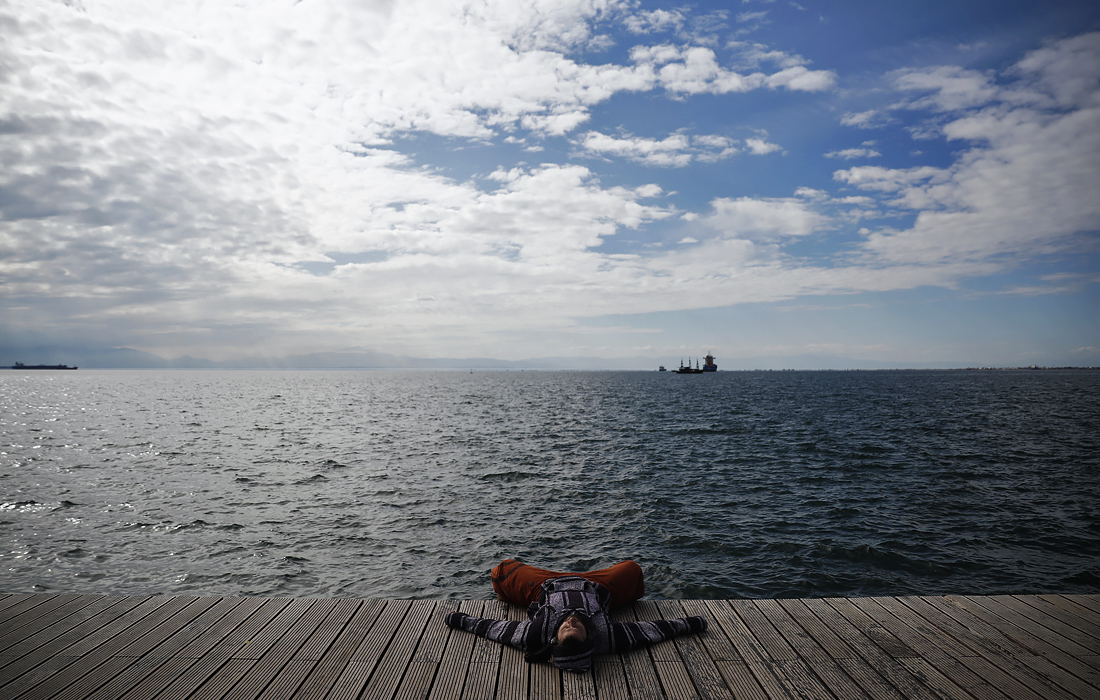 Мужчина отдыхает на берегу моря в северном греческом городе Салоники
