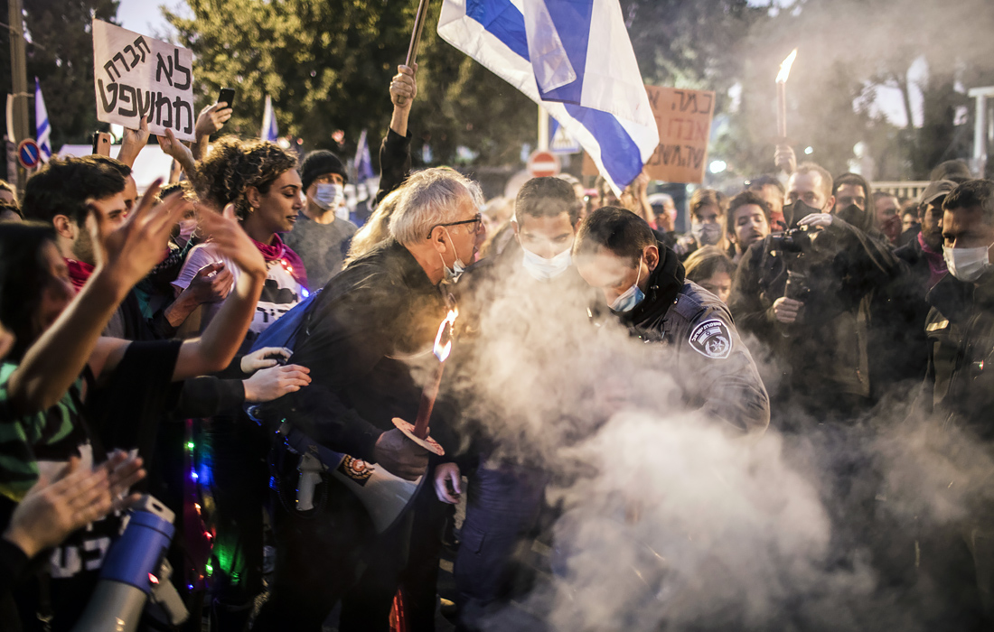 Протестующий спорит с полицейскими во время акции в Иерусалиме, участники которой требовали отставки премьер-министра Израиля Биньямина Нетаньяху в связи с уголовными делами о коррупции.