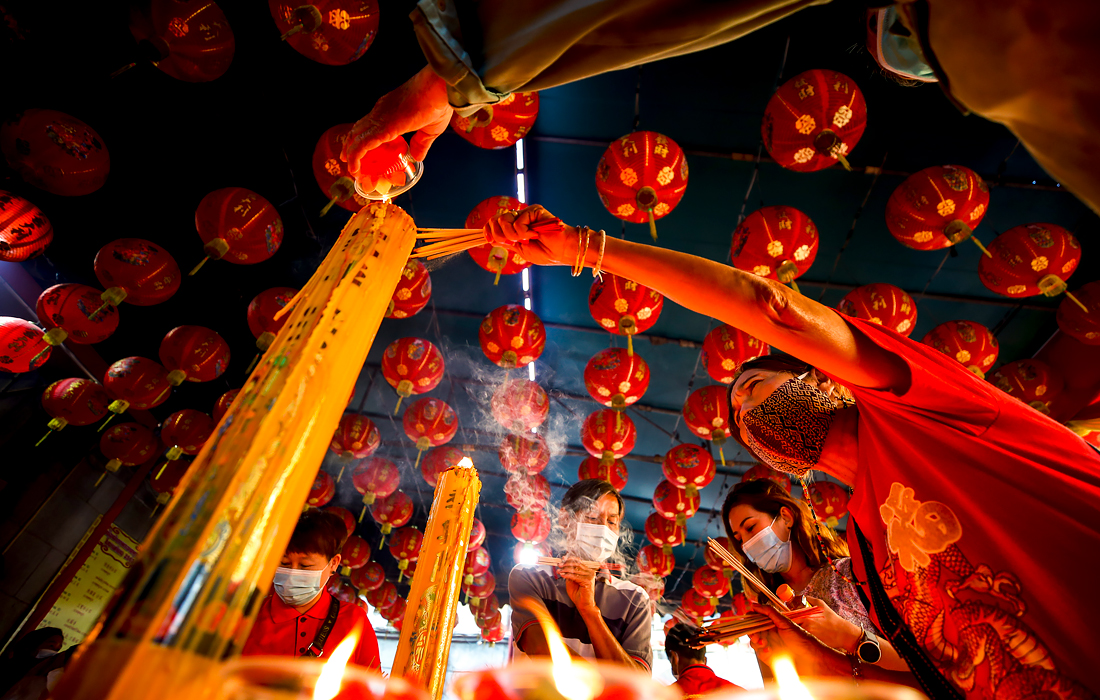 Верующие зажигают ароматические палочки в храме в Бангкоке, Таиланд