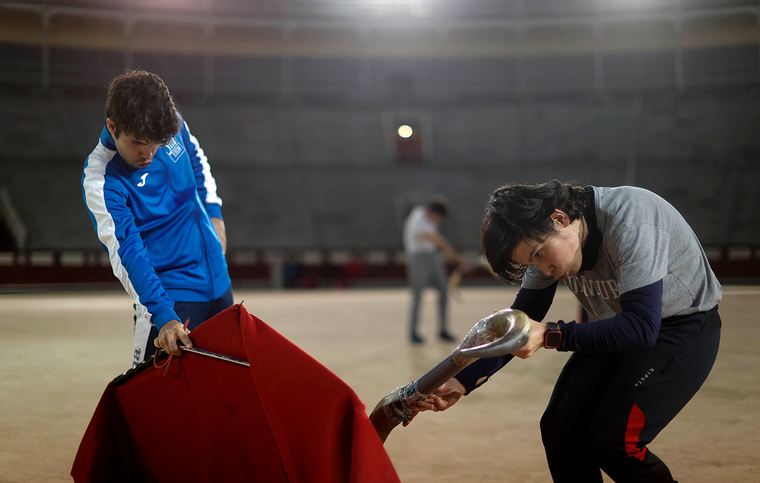 Подростки выполняют упражнения в парах, один из мальчиков изображает быка, а другой - тореадора