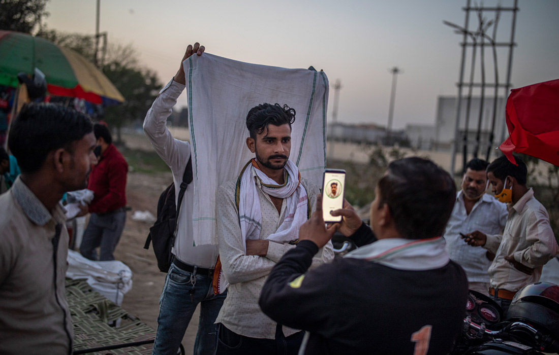 Продавец SIM-карт фотографирует клиента в пригороде Нью-Дели, Индия