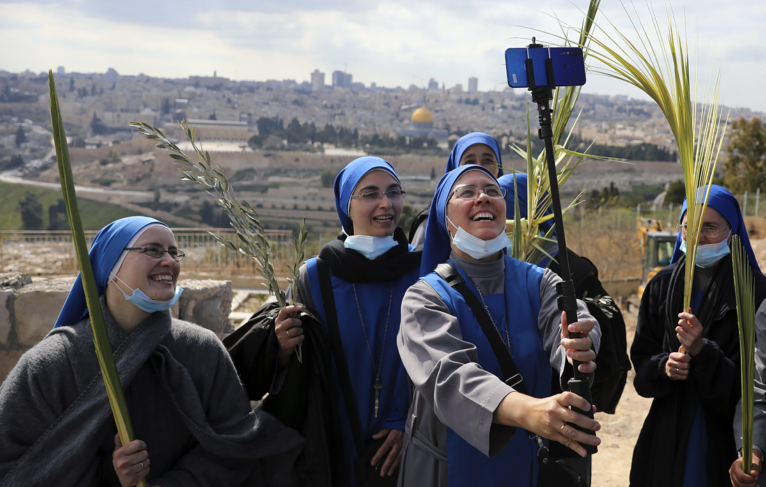 Монахини позируют для селфи во время празднования Вербного воскресенья в Иерусалиме
