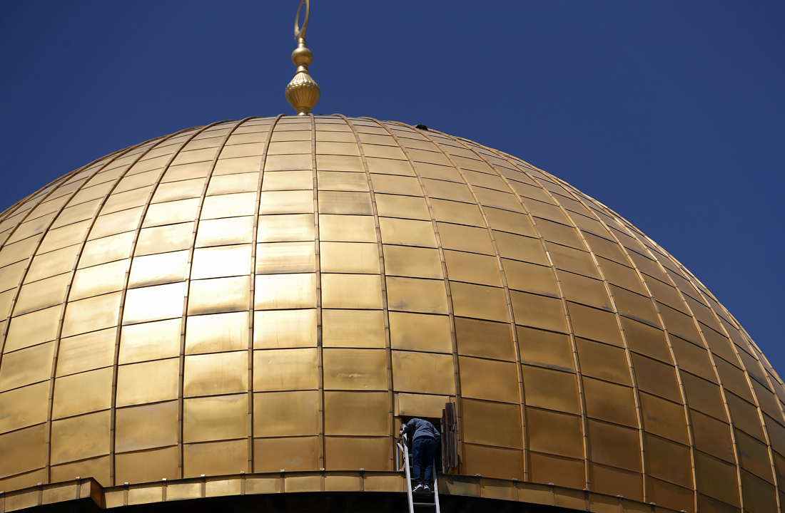 Палестинский служащий поднимается по лестнице на купол мечети Аль-Акса в старом городе Иерусалима во время второй пятничной молитвы Рамадана