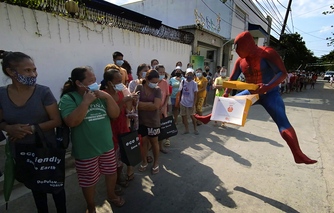 Филиппинец в костюме Человека-паука раздает бесплатную еду пострадавшим от карантинных мер в городе Лас-Пинас, к югу от Манилы
