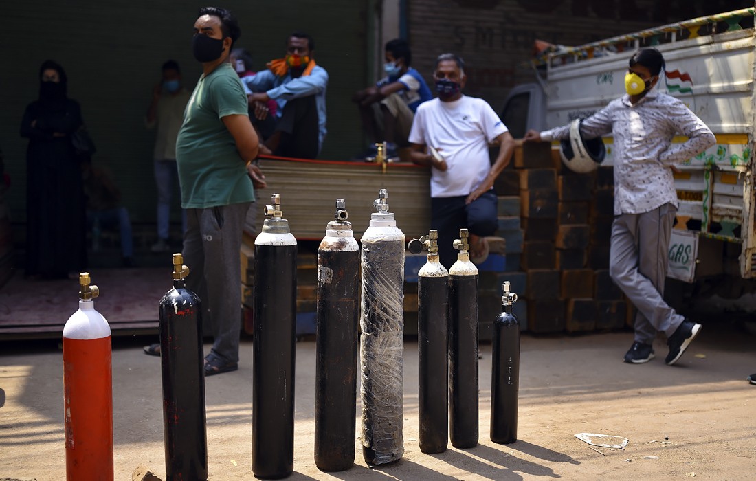 Индийцы стоят в очереди, чтобы заполнить кислородные баллоны в магазине по продаже кислорода в Нью-Дели