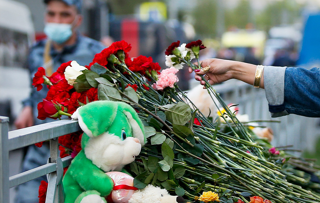 Жители Казани несут цветы и детские игрушки к тротуарному ограждению неподалеку от учебного заведения