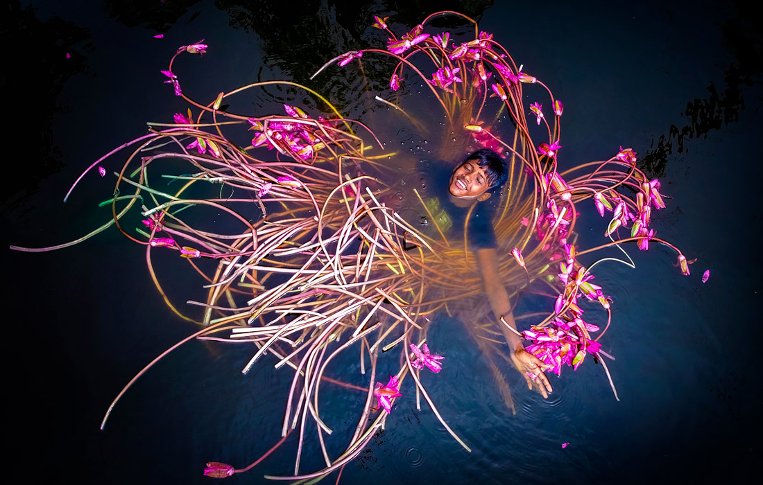 Мальчик плавает среди водяных лилий в Бангладеш