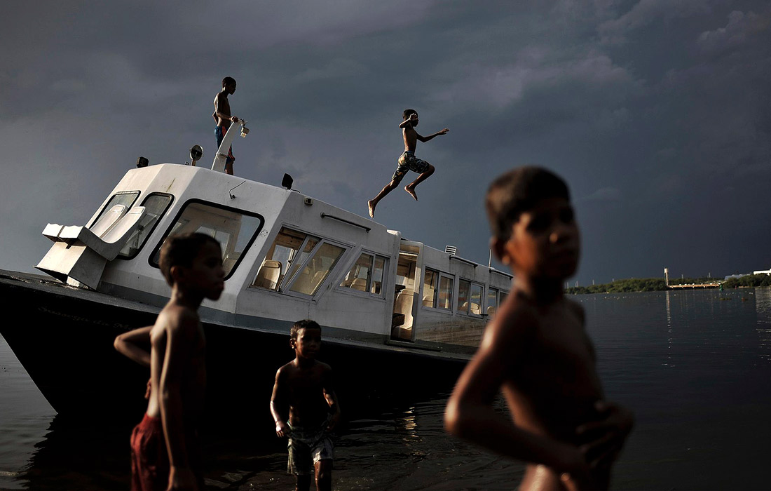 Дети из фавел купаются в загрязненных водах залива Гуанабара в Рио-де-Жанейро, Бразилия