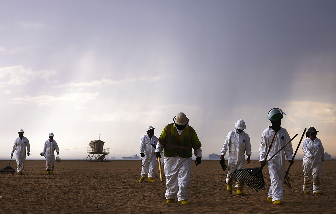 Рабочие, убиравшие пляж американского города Хантингтон-бич после разлива нефти, уходят в преддверии шторма