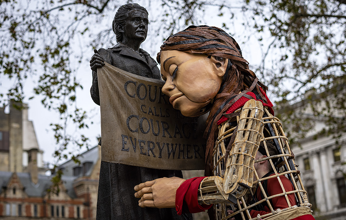 Путешествующая по Европе кукла Маленькая Амаль обнимает статую суфражистки и феминистки Миллисент Фосетт на Парламентской площади в Лондоне в знак протеста против законопроекта о национальности и границах. Амаль - действующее лицо, цель которого - привлечение внимания внимания к проблемам мигрантов.