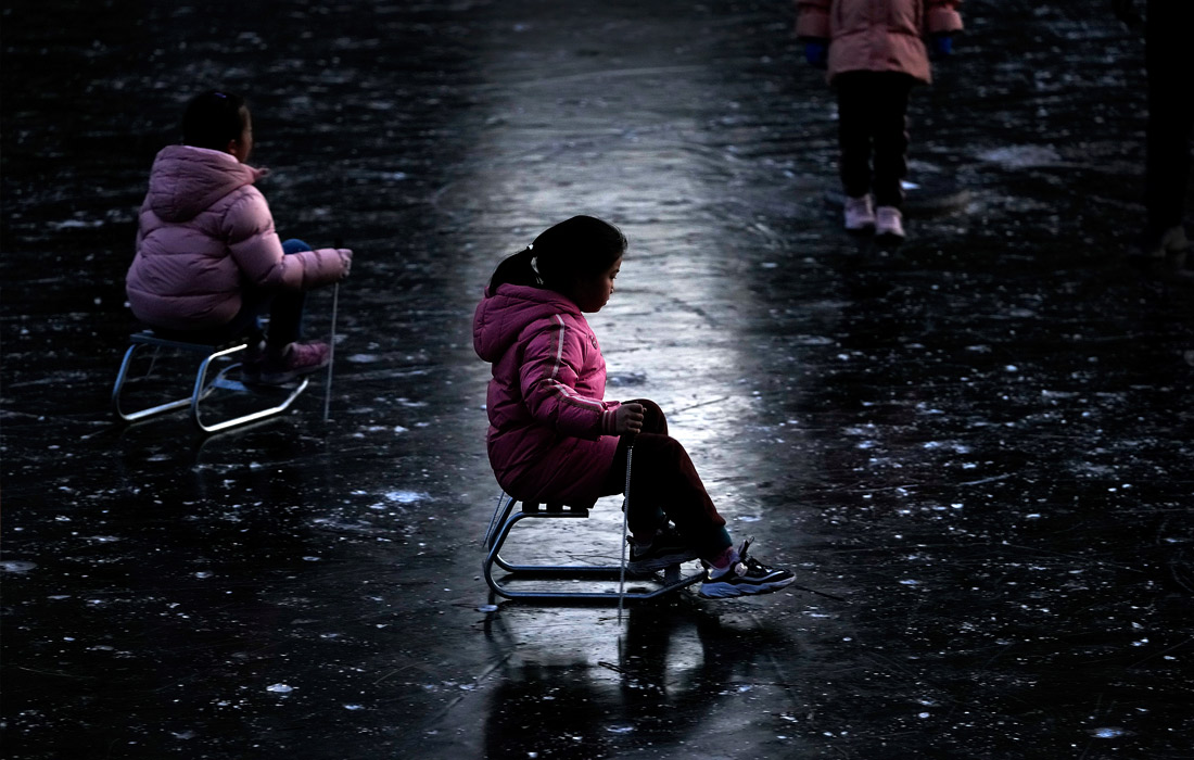 Дети катаются по замерзшей реке в Пекине