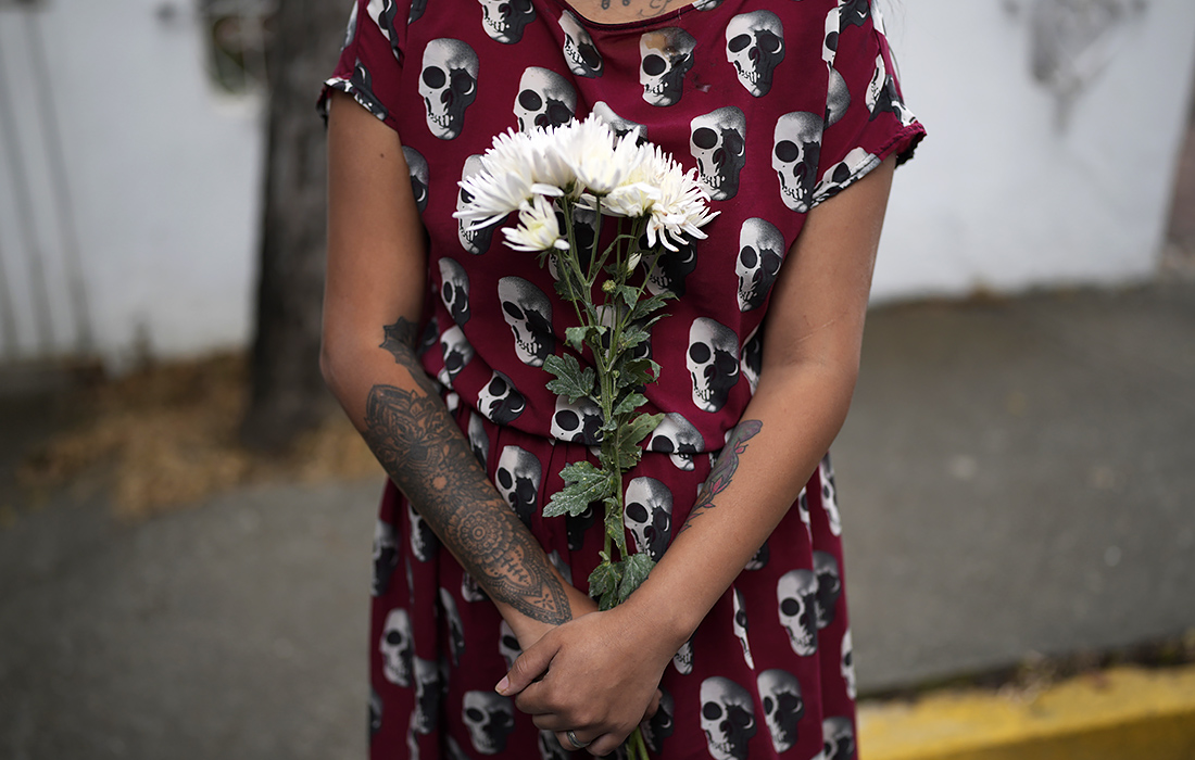 Женщина держит букет цветов во время акции протеста против стрельбы офицеров Тринидада по лодке с мигрантами перед посольством Тринидада и Тобаго в Каракасе