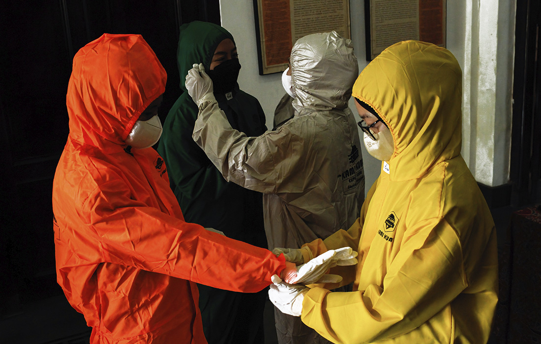 3 марта. Посетители в защитных костюмах перед входом на фотовыставку о пандемии в Индонезии.