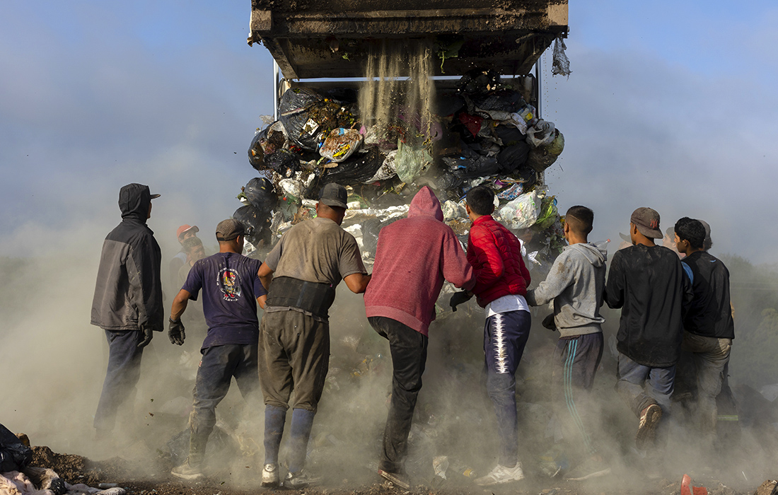 Заработок на самой большой свалке Аргентины. На фото: мужчины собираются вокруг мусоровоза, чтобы найти среди отходов пригодные к продаже вещи.