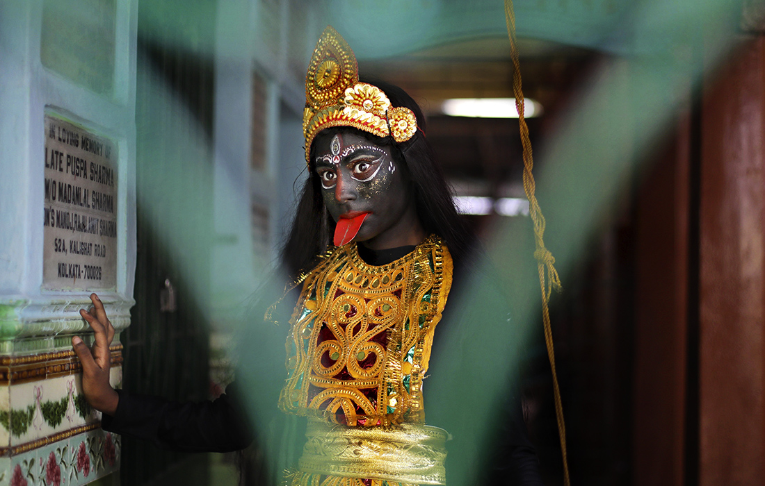 Девушка, одетая как индуистская богиня Кали, ждет начала религиозного шествия во время фестиваля Гаджан в Калькутте