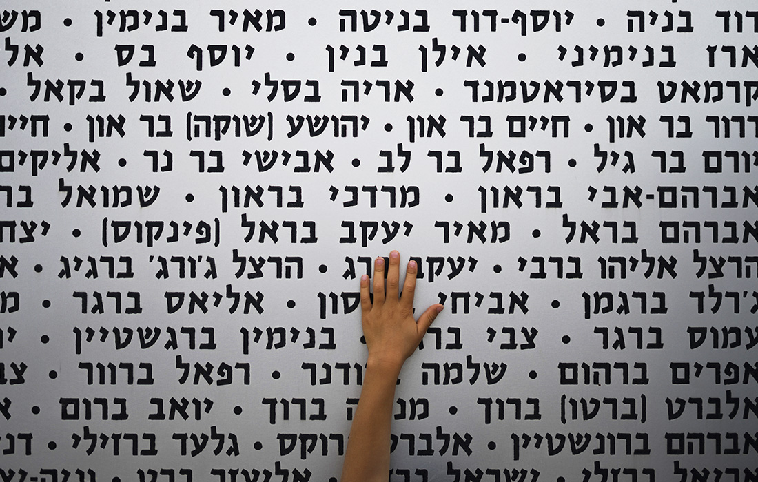 Ребенок прикасается к мемориальной стене в День памяти павших солдат в Латруне, Израиль