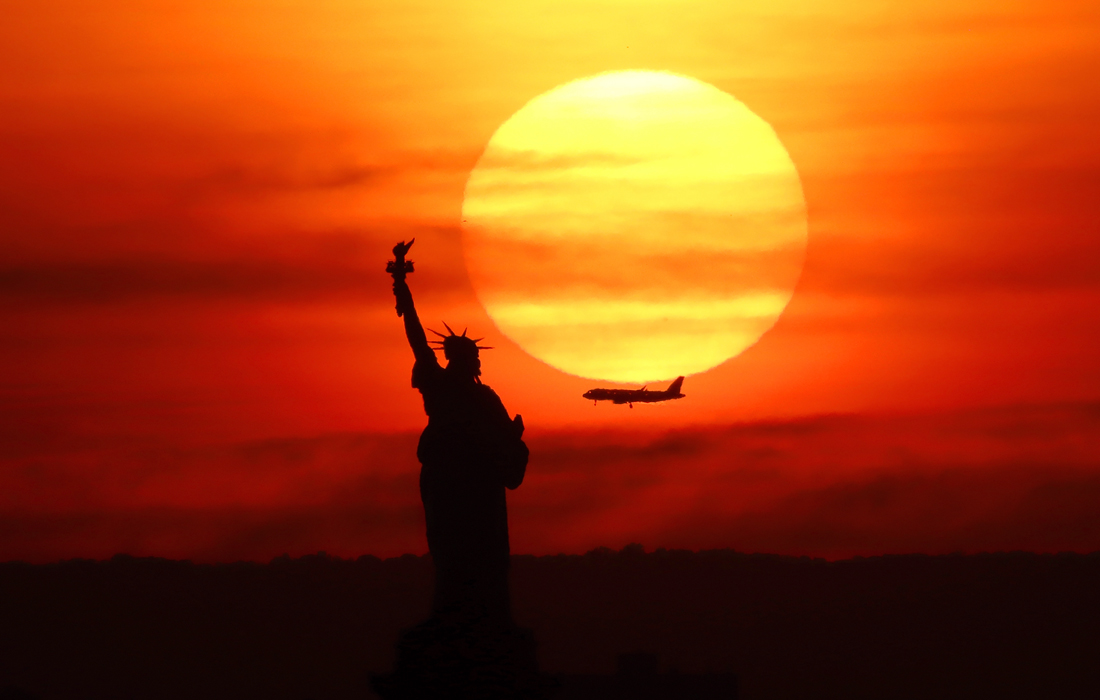Заход солнца за статуей свободы в Нью-Йорке