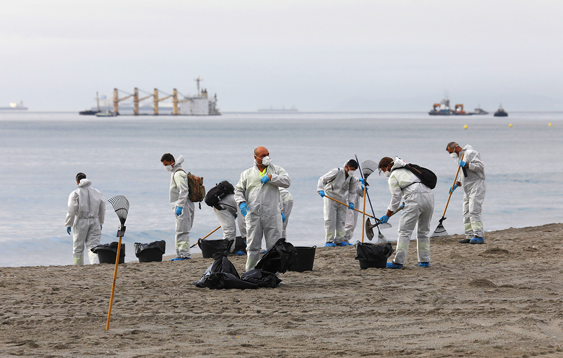 Муниципальные работники очищают пляж после разлива нефти с теплохода "ОС 35" в Испании