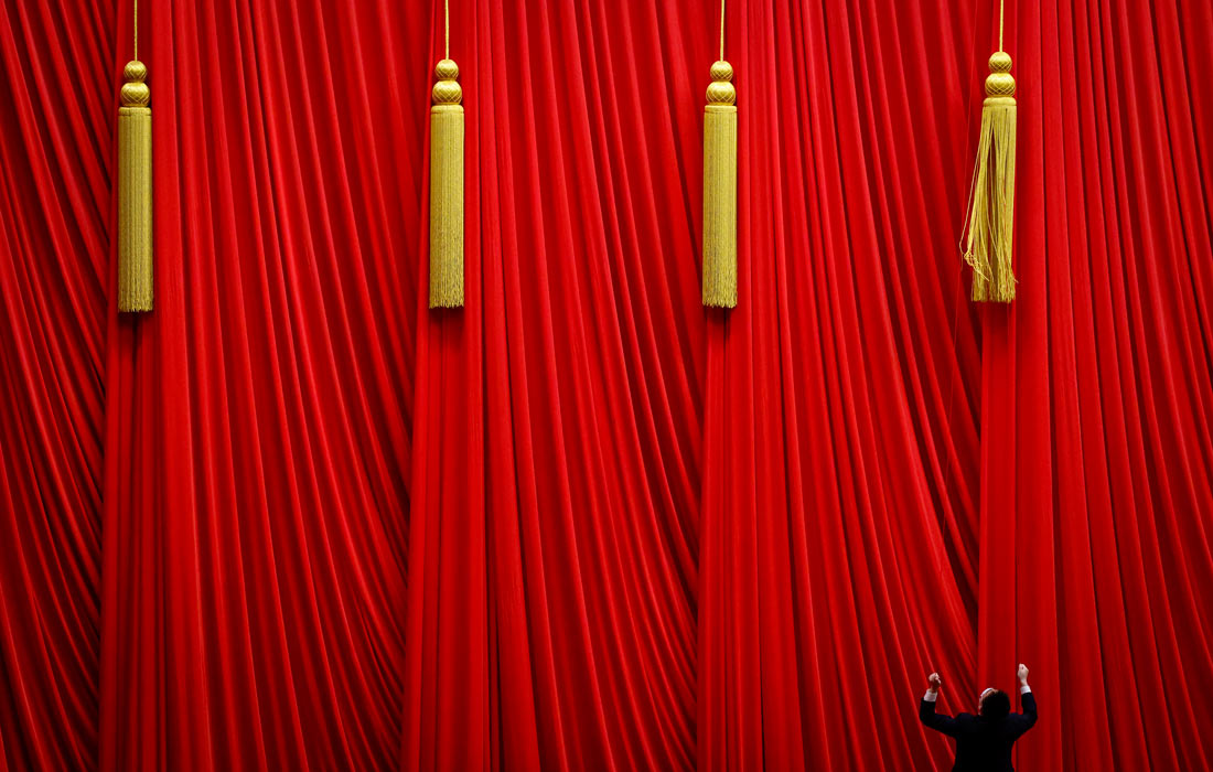 Мужчина поправляет шторы перед Пятой сессией Всекитайского собрания народных представителей в Пекине