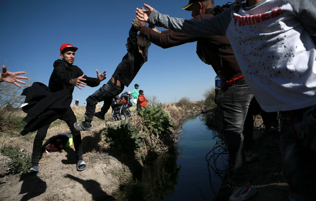 Мигранты пересекают реку Рио-Гранде на границе с США