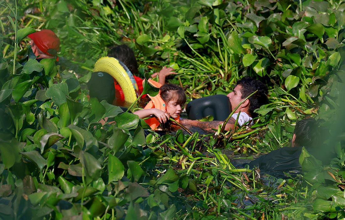 Мигранты пробираются через заросли на реке Рио-Гранде, чтобы въехать в Соединенные Штаты