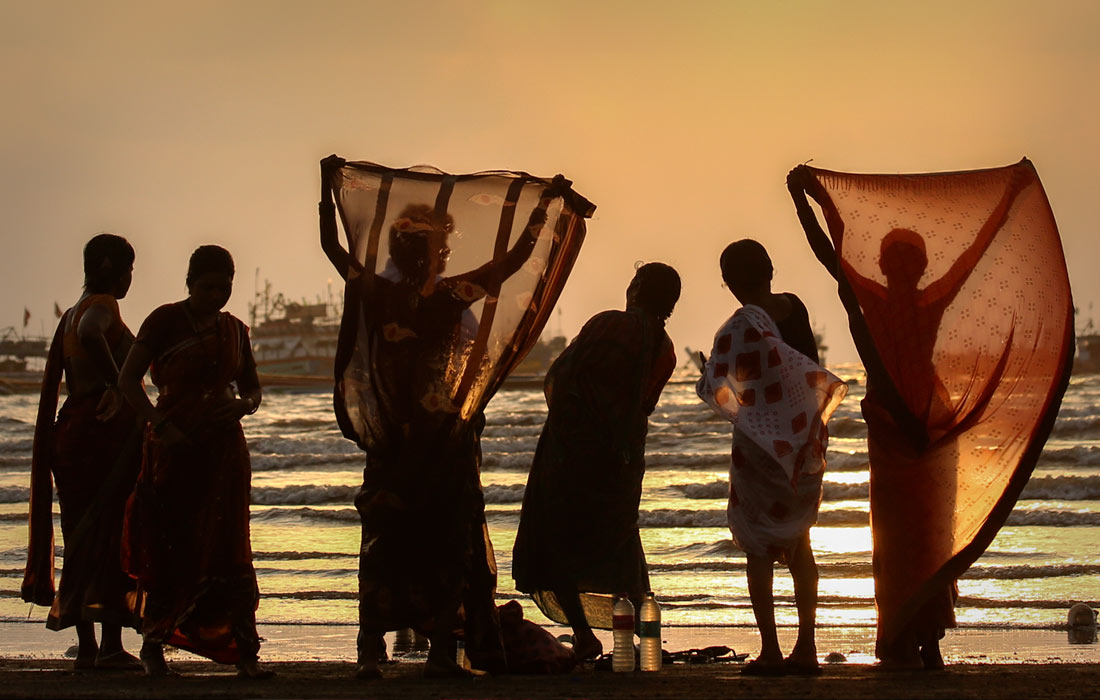 Женщины сушат одежду на пляже в Мумбаи, Индия