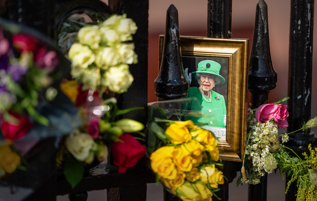 Люди оставляют у ворот и стен цветы и написанные от руки послания покойной королеве