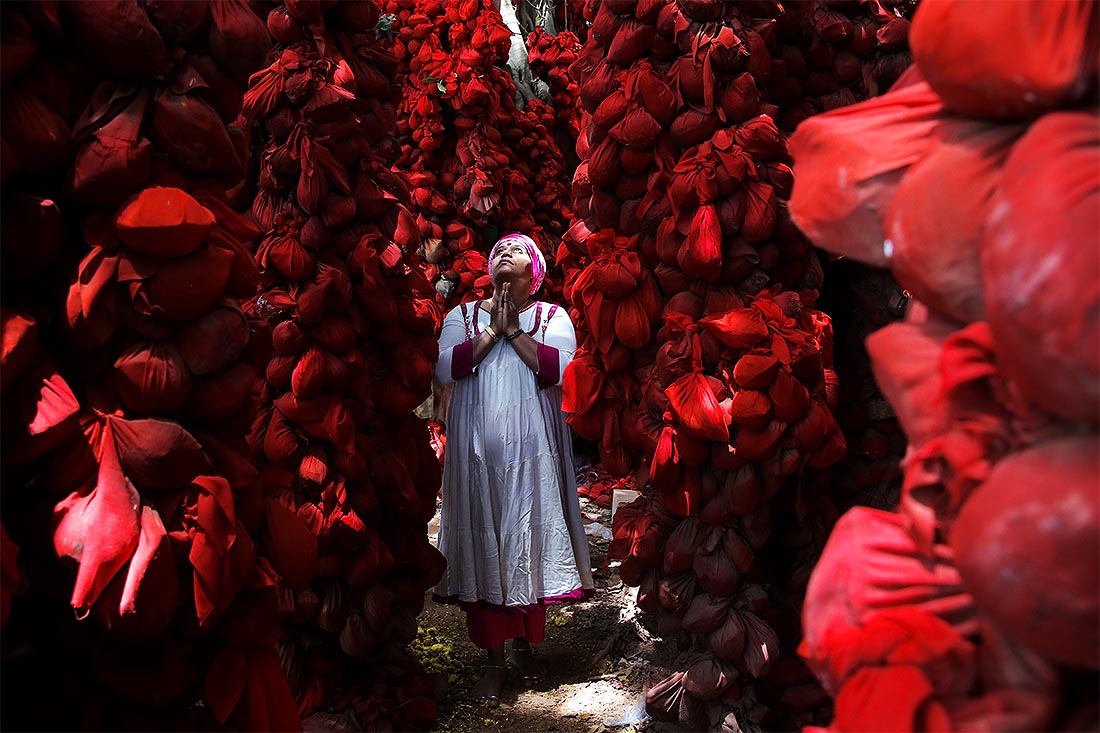 В Бангалоре верующие молятся среди подношений - кокосовых орехов, завернутых в красную ткань и привязанных к баньяну в храме Катерамма