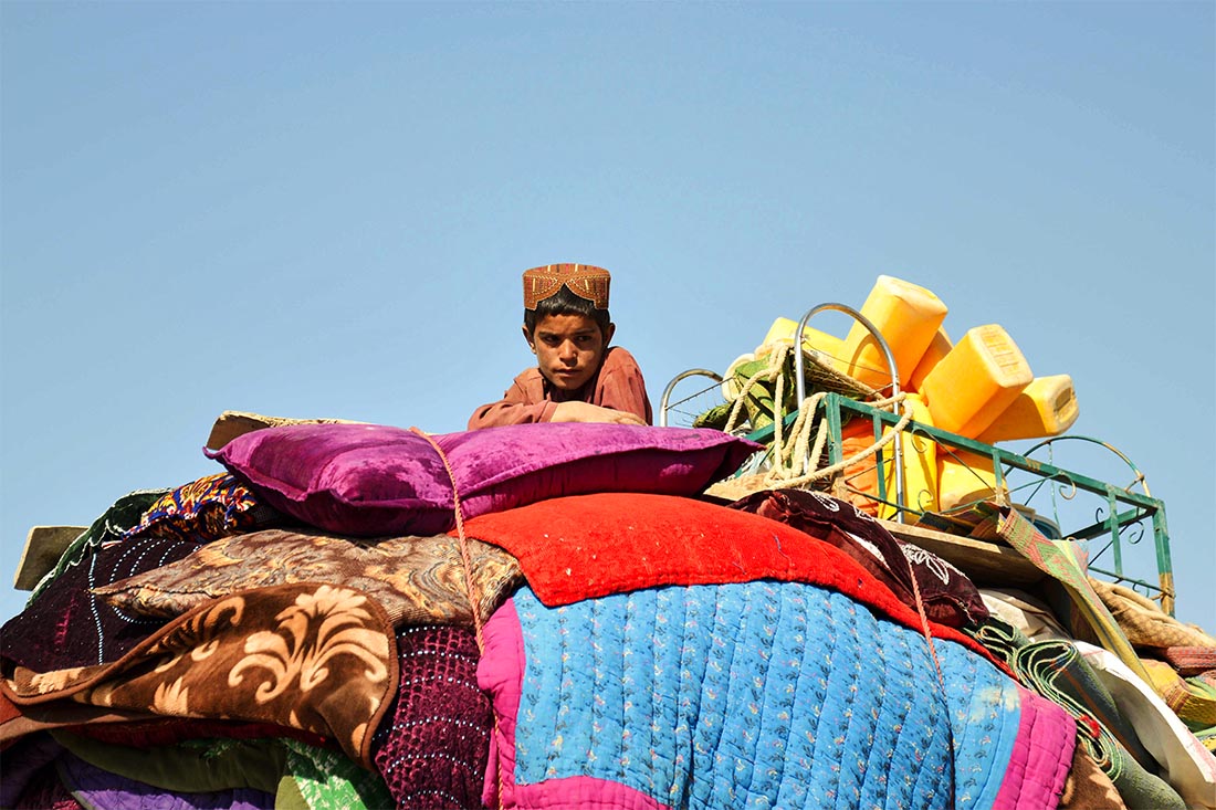 Ребенок-беженец из Афганистана сидит на багаже ​​во время пересечения пакистанской границы в Чамане