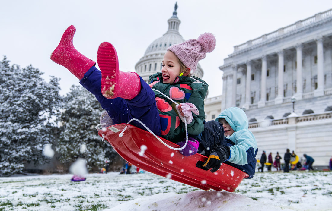 Дети катаются на санках перед западным фасадом Капитолия США